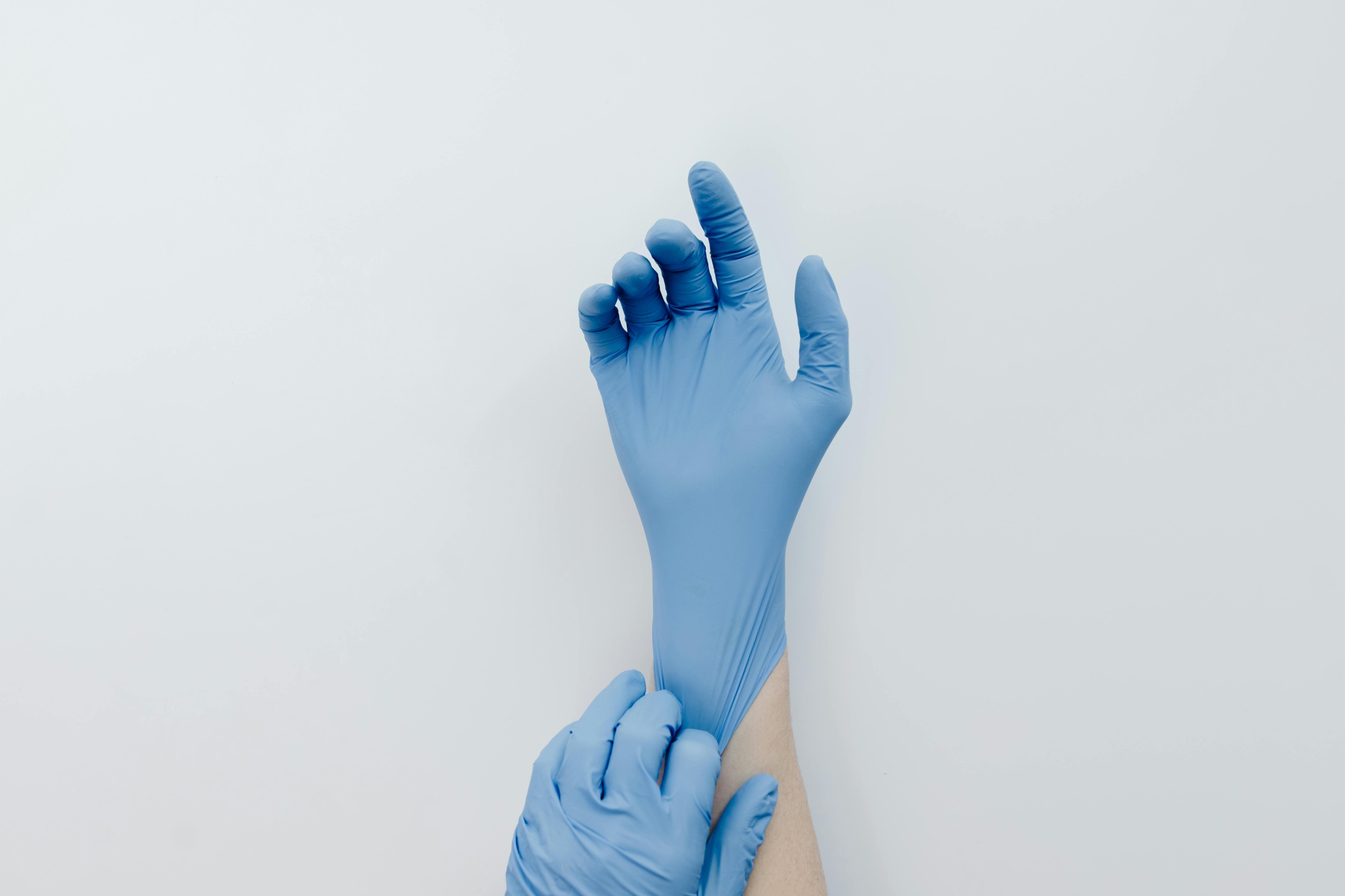 Hand mit Handschuh wird erhoben vor hellem Hintergrund.