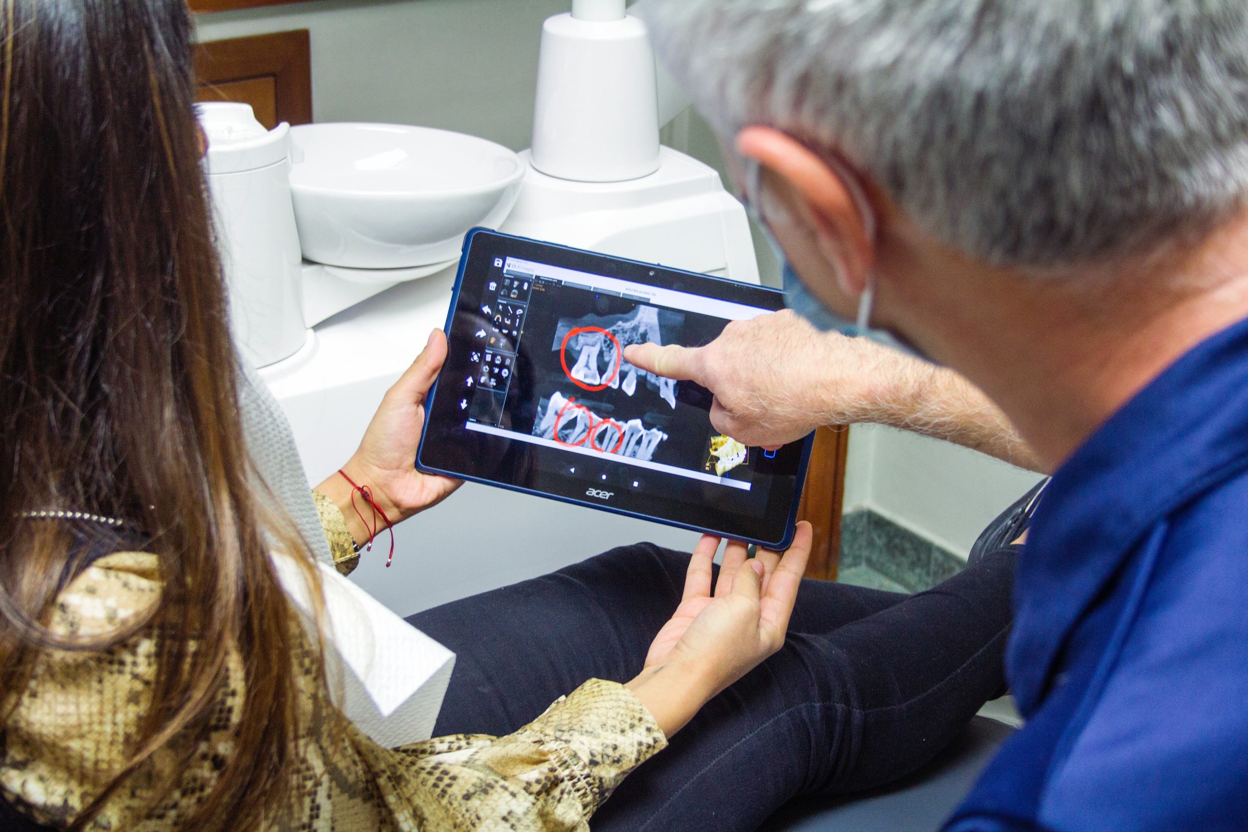 Behandler erklärt einer Patientin eine endodontische Befundsituation anhand einer digitalen Röntgenaufnahme auf einem Tablet.